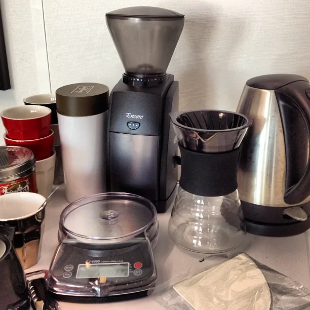 HARIO V60 Drip Decanter with black band, right of the grinder in a coffee setup; surrounding equipment is not included