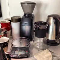HARIO V60 Drip Decanter with black band, right of the grinder in a coffee setup; surrounding equipment is not included