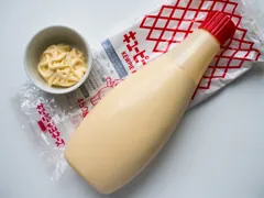 Japanese Kewpie standard mayonnaise 450g bottle with red cap and red-grid outer bag, beside a bowl of mayonnaise; older 2016 packaging